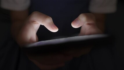 Hand of little girl using smartphone at night, typing message or chat