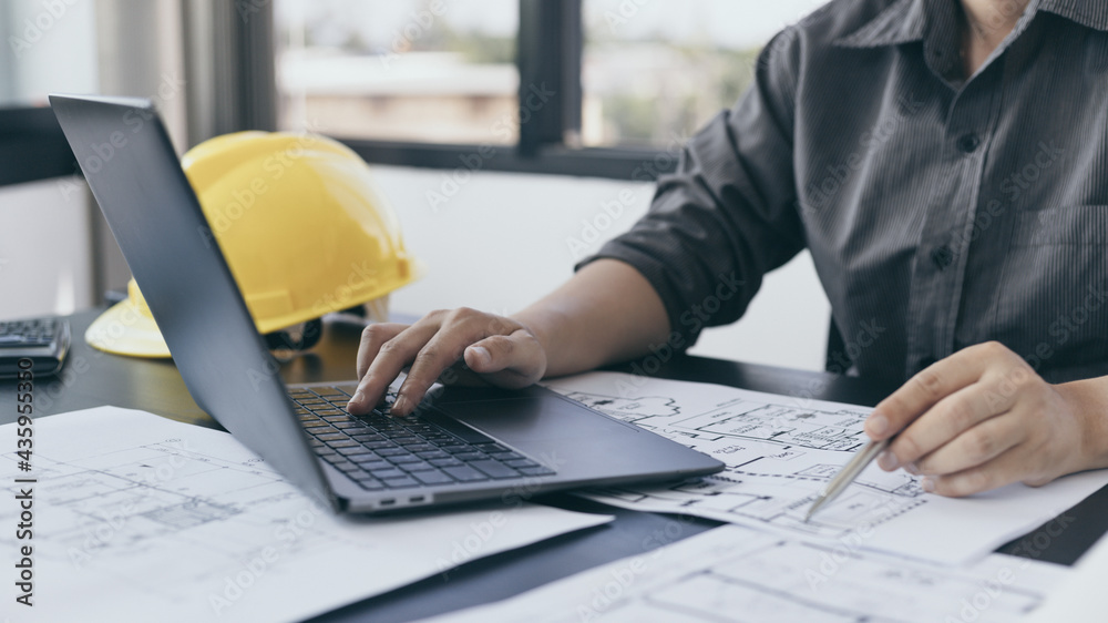 Young man with a laptop plotting a system of building structures in ...