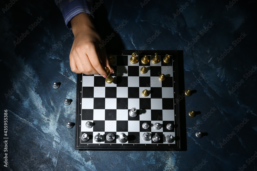 Woman playing chess on color table