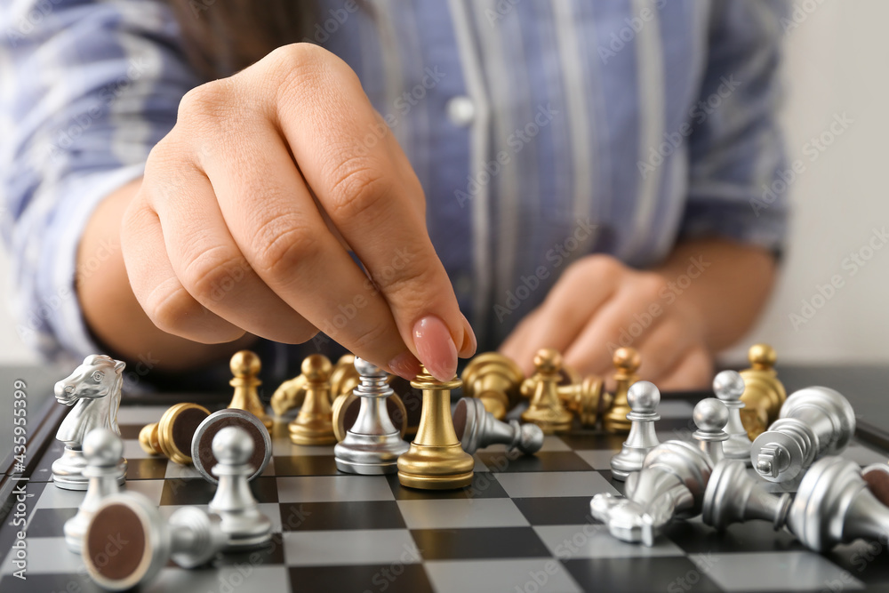 Woman playing chess at table, closeup