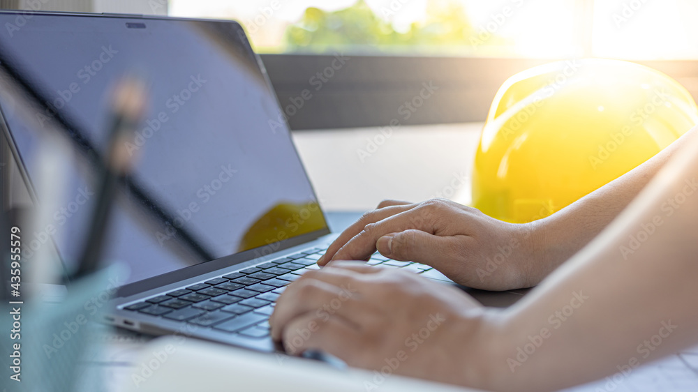 Young man with a laptop plotting a system of building structures in ...