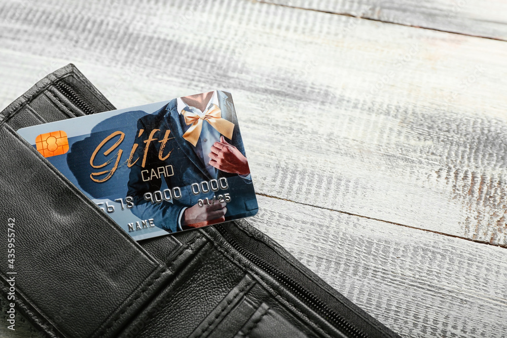 Wallet with gift card on color wooden background