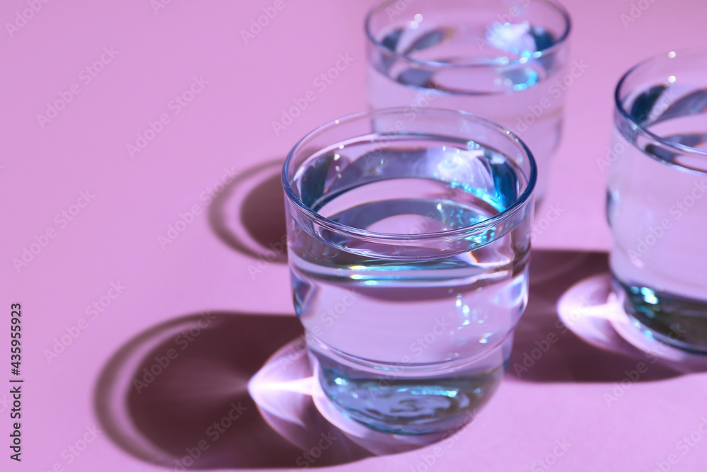 Glasses of water on color background