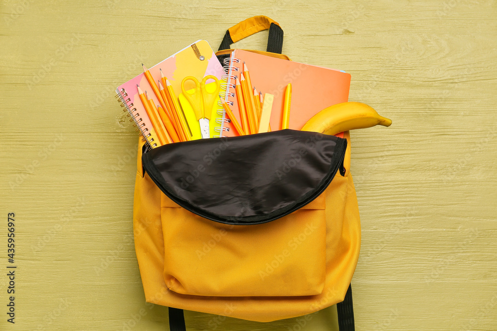 School backpack and stationery on color wooden background
