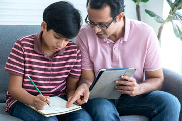 Indian father helps him check the accuracy of his child's math homework, Educate at home