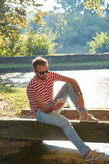 Wall Mural - Young adult man using modern smartphone in the park.