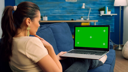 Back shot of caucasian female typing and looking at laptop computer with mock up green screen chroma key. Business woman searching the web for company information using isolated pc