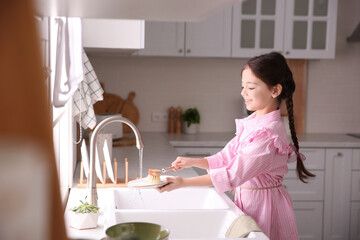 Poster - Little girl washing dishes in kitchen at home