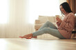 © New Africa - Woman sitting on warm floor in living room. Heating system
