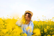 Young Woman With Yellow Flowers On Field Against Sky