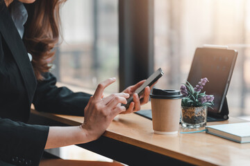 Image of a businesswoman hand sitting using smartphone at a coffee shop.