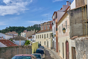 Sticker - Colorful buildings and cars in a village in the background of green trees and blue sky in Portugal