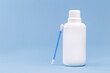 hydrogen peroxide, in white plastic bottle, with cotton swab and isolated blue background, medicine concept, medicine for wounds and small cuts