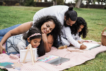 Wall Mural - happy indian family having fun painting with children outdoor at city park - main focus on mother fa