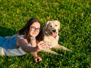 Wall Mural - brunette woman playing with a dog white golden retriever on the grass in park.