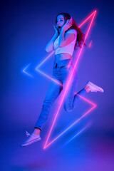 Caucasian woman's portrait isolated on blue studio background in multicolored neon light with geometric luminescent shapes