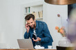 © LIGHTFIELD STUDIOS - smiling freelancer pointing at laptop while talking on mobile phone