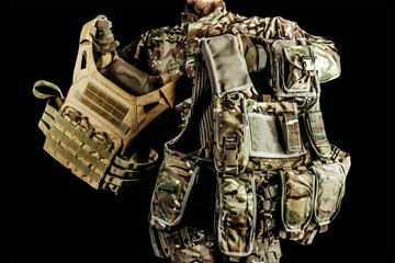 Wall Mural - Photo of soldier holding various types of camouflaged armored vests on black background.