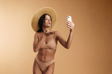 Wall Mural - Young woman in swimsuit gesture while taking selfie on cellphone