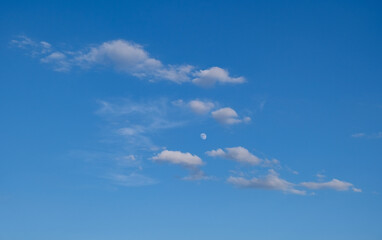 the moon among the clouds in the blue sky
