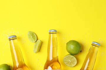 Bottles of beer, lime and salt on yellow background