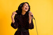 Photo of pretty cheerful dark skin girl closed eyes open mouth singing loud isolated on yellow color background