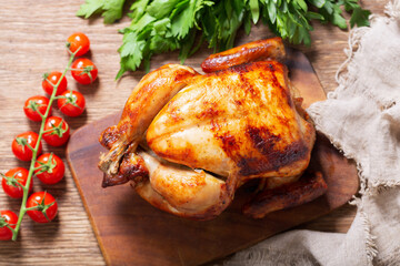 Wall Mural - whole roasted chicken on a wooden board, top view