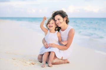 mother with little daughter playing on ocean beach, maldives. family on the beach concept.