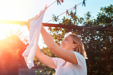 A Young Caucasian Smiling Woman Hanging Laundry