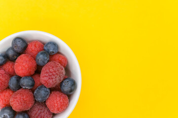 Wall Mural - Top view of fresh blueberry and raspberry on a white bowl