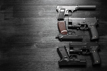 Airsoft Guns On The Black Wooden Table Flat Lay Background With Copy Space.