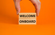 Welcome onboard symbol. Wooden blocks with words 'Welcome onboard' on beautiful orange background. Businessman hand. Business and welcome onboard concept. Copy space.