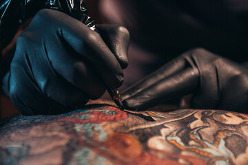 Wall Mural - Hands of a tattoo artist wearing black gloves and holding a machine