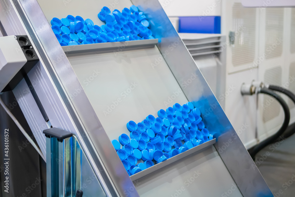 Many blue plastic bottle caps moving on conveyor belt of automatic ...