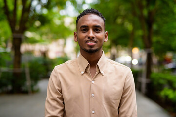 Portrait of handsome black young African businessman outdoors at park