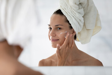 happy cosmetic product consumer satisfied with moisturizing antiage cream. young woman spreading nou