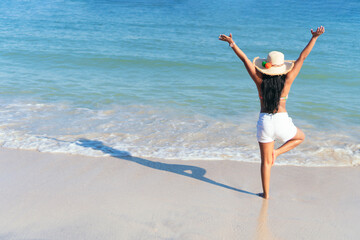 Black Woman standing in front of the ocean with her hands up