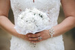 Closeup shot of a bride holding a bridal bouquet with artificial roses