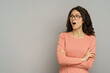© DimaBerlin - Excited woman with open mouth looking aside to empty space. Shopping sales, reduced prices and discount concept. Shocked positive millennial curly female in eyewear over gray studio wall background