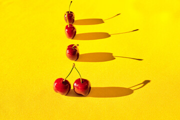 Sticker - Row of five red cherries with shadow isolated on a yellow background - space for text