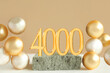 Number 4000 on a concrete podium and volumetric golden balls on a beige background. Copy space..