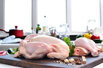 Canvas Print - Fresh raw chicken with ingredients for cooking on a wooden cutting board in the kitchen