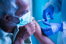 Senior Elderly Patient With Mask Getting Vaccination Or Jab At Hospital - Doctor In Protective Hazmat Suit Treating Covid Patient Injecting Anti-viral Vials At Covid Care Centre