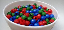 Red, Green And Blue Colored Beads In A White Bowl