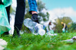 Hand of man picking up bottle into garbage bags while cleaning area in park. Volunteering, charity, people, ecology concept. Closeup volunteer collecting plastic trash in forest. World clean up m day