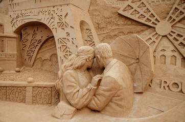 A sculpture of lovers made of sand against the backdrop of the Eiffel Tower. Parisian mood.