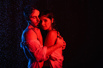 Wall Mural - red and blue colors filters picture of wet passionate romantic couple hugging in water drops on black background