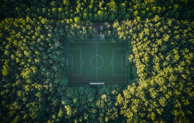 Aerial top down view above the people playing football on a pitch among the forest