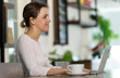 © Bangkok Click Studio - Beautiful young Caucasian woman freelancer in white long-sleeved shirt sitting at ease in cafe on afternoon and typing on laptop for working online business