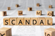 Scandal - word wooden blocks with letters, affray fracas scandal concept, random letters around, paper background